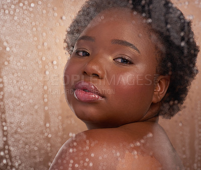 Buy stock photo Studio portrait of a beautiful young woman posing against a brown background surrounded by water droplets