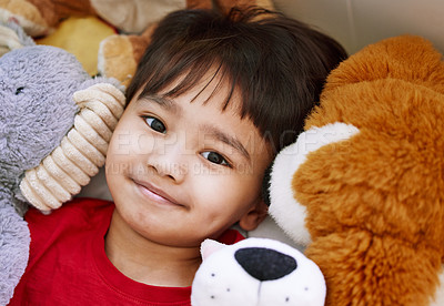 Buy stock photo Portrait of an adorable little boy lying on a bed with his stuffed toys at home