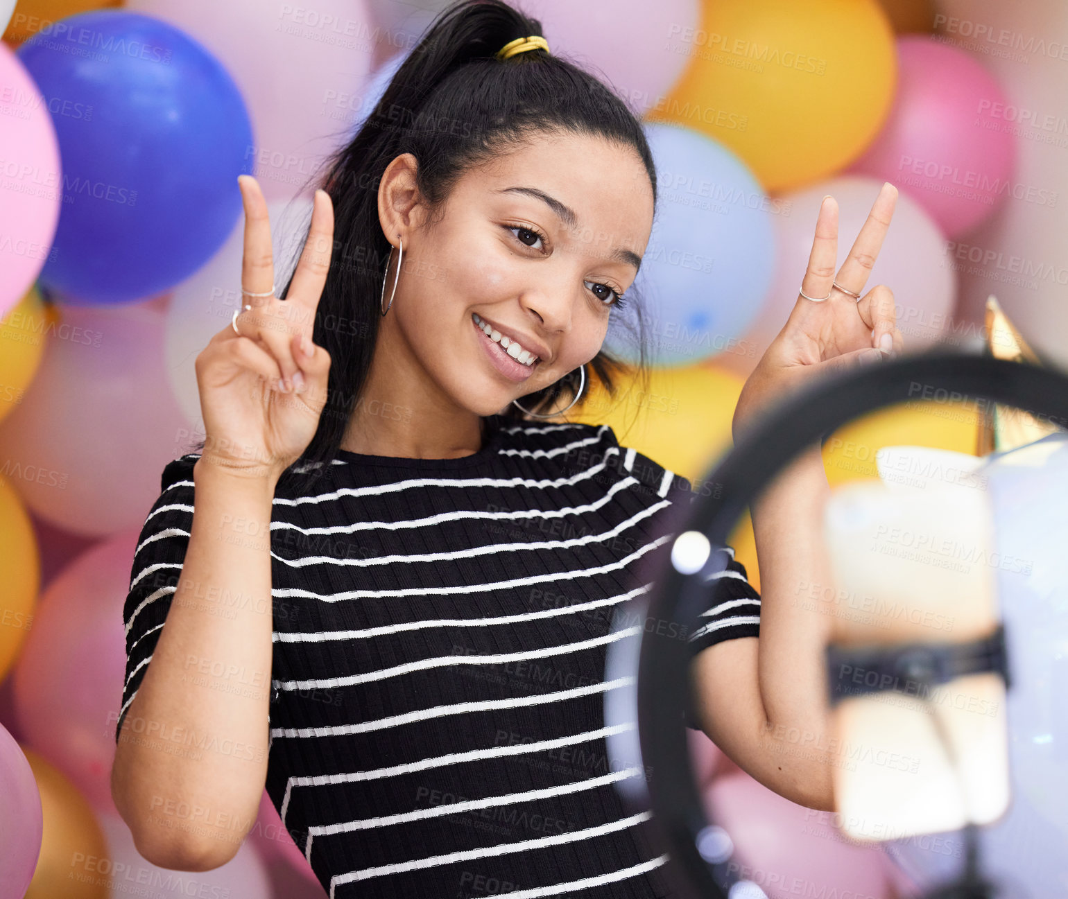 Buy stock photo Shot of a happy young woman recording herself with a smartphone against a background of balloons