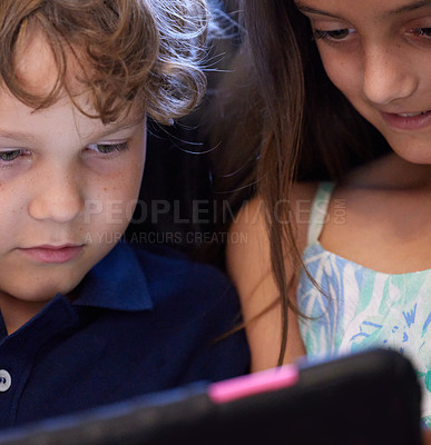 Buy stock photo Shot of a little boy and girl using a digital tablet while sitting together