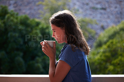 Buy stock photo Shot of a young woman enjoying a cup of coffee on the balcony of her home