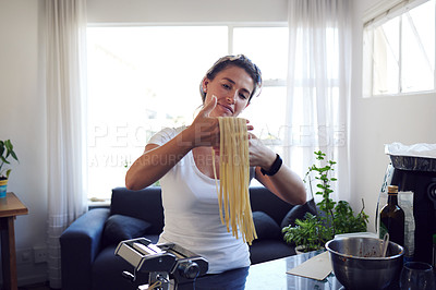 Buy stock photo Cropped shot of an attractive young woman cooking homemade pasta at home