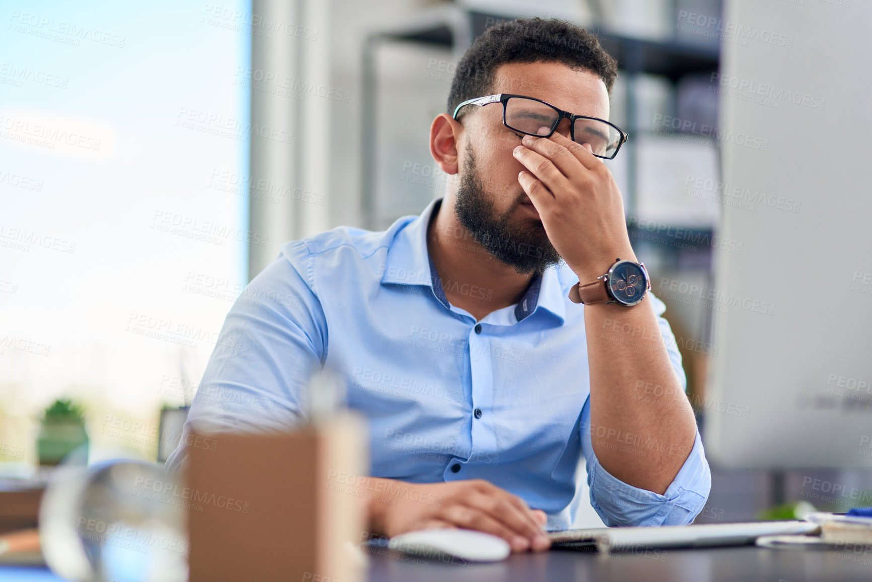 Buy stock photo Cropped shot of a handsome young businessman sitting alone in his office and feeling stressed during the day