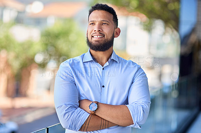 Buy stock photo Cropped shot of a handsome young businessman standing outside and looking contemplative with his arms crossed