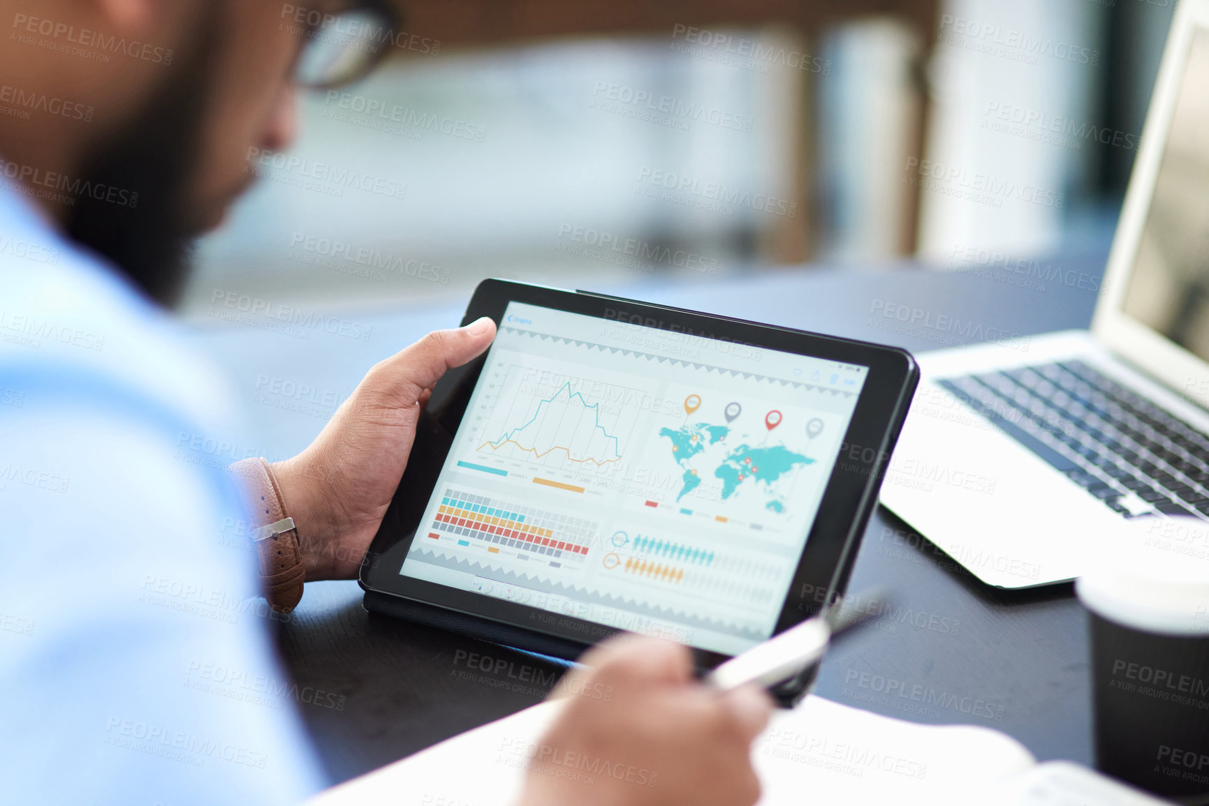 Buy stock photo Cropped shot of an unrecognizable businessman sitting alone in his office and using a digital tablet