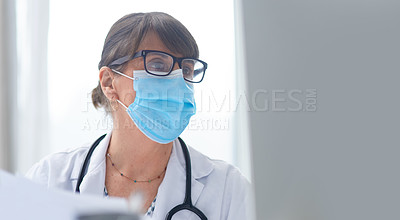 Buy stock photo Shot of a mature female doctor wearing a mask in her office