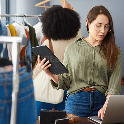 Buy stock photo Shot of a woman using a digital tablet while working in a clothing store