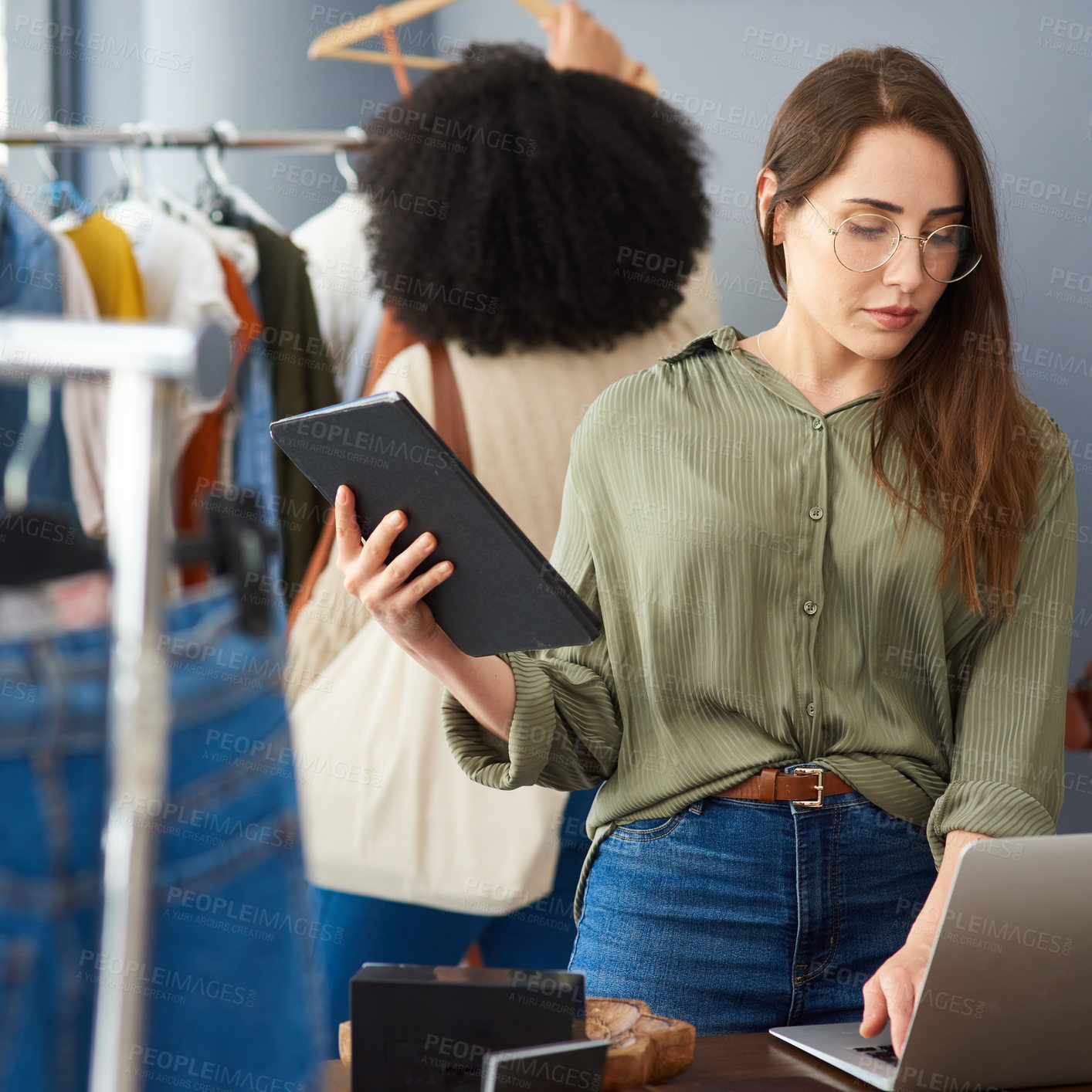 Buy stock photo Shot of a woman using a digital tablet while working in a clothing store