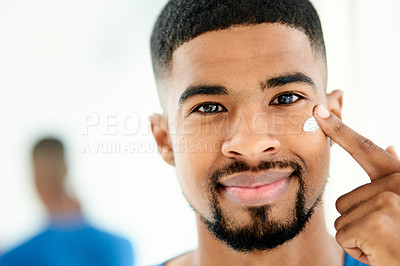 Buy stock photo Shot of a happy young man applying moisturizer in his bathroom