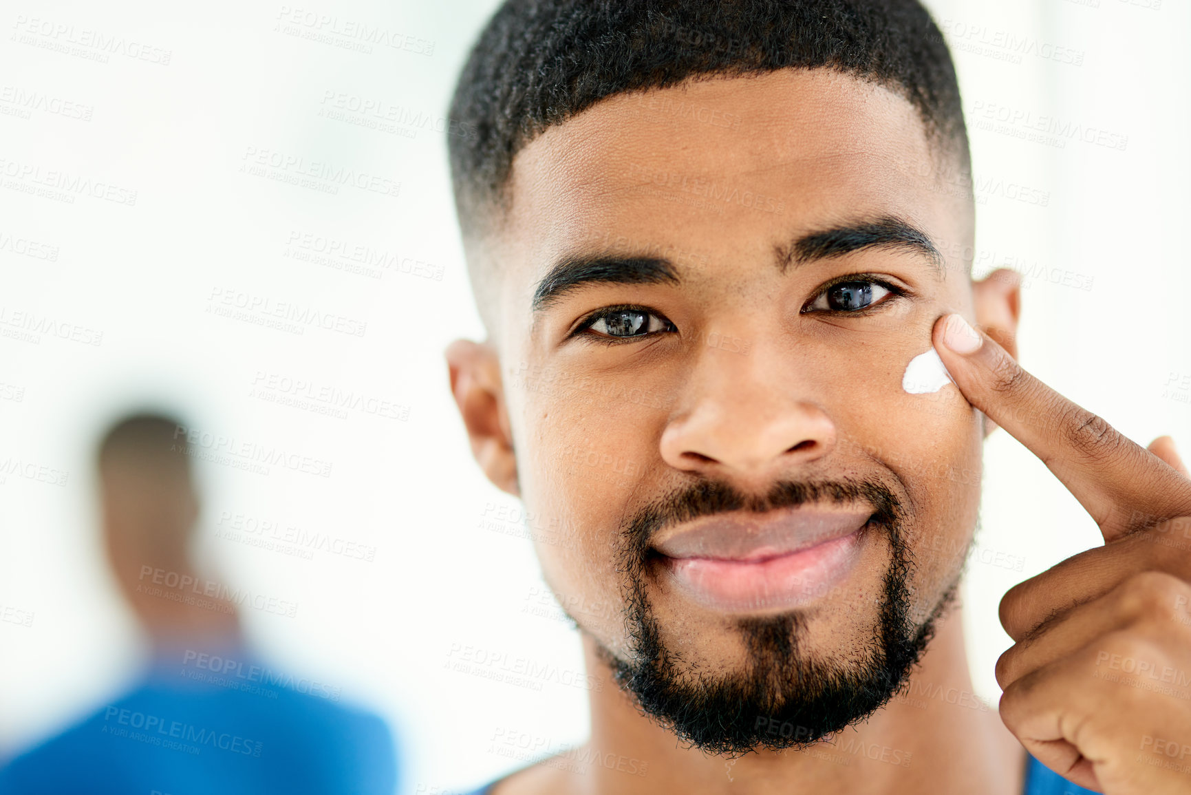 Buy stock photo Shot of a happy young man applying moisturizer in his bathroom