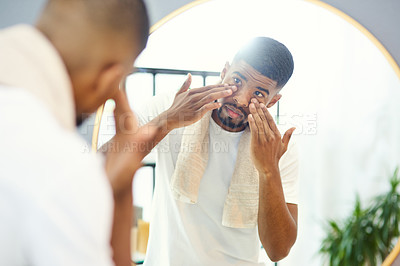 Buy stock photo Young man applying face product in his bathroom mirror