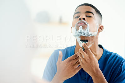 Buy stock photo Shot of young man focusing on shaving throughly
