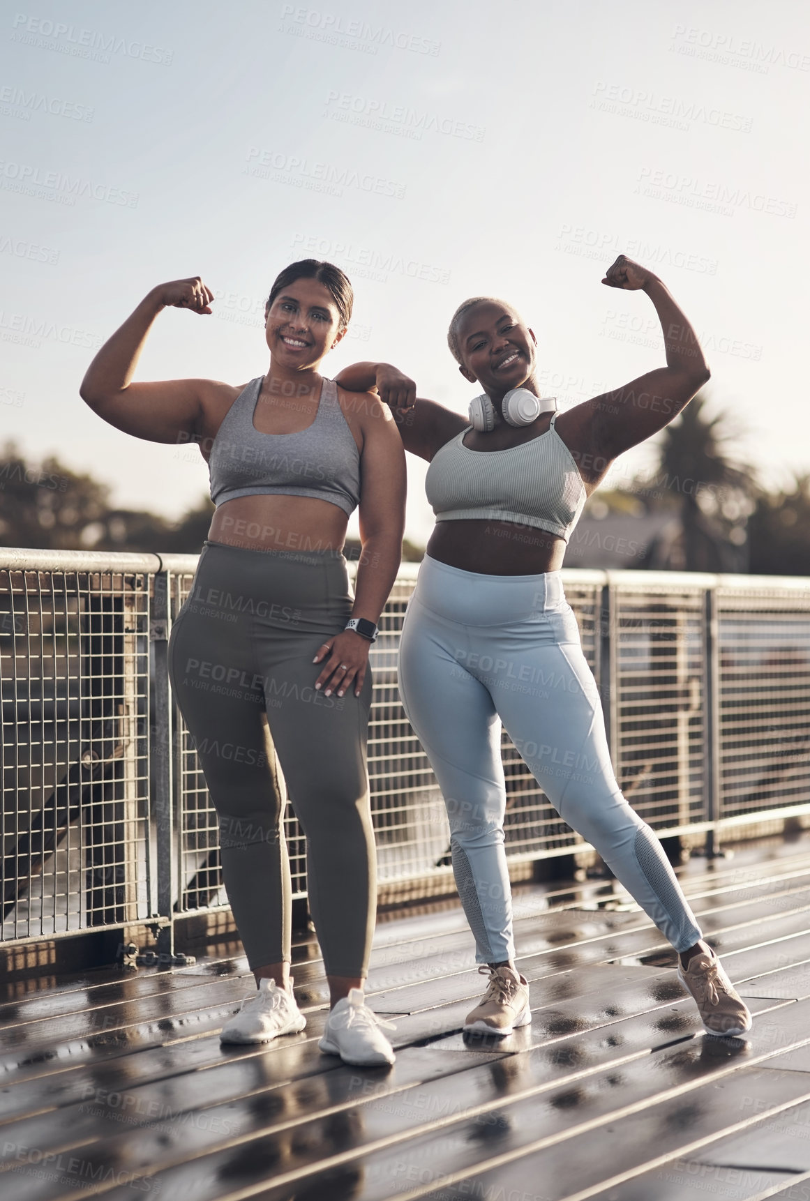 Buy stock photo Shot of two young women flexing while out for a run