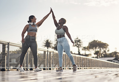 Buy stock photo Shot of two young women giving each other a high-five while out for a workout