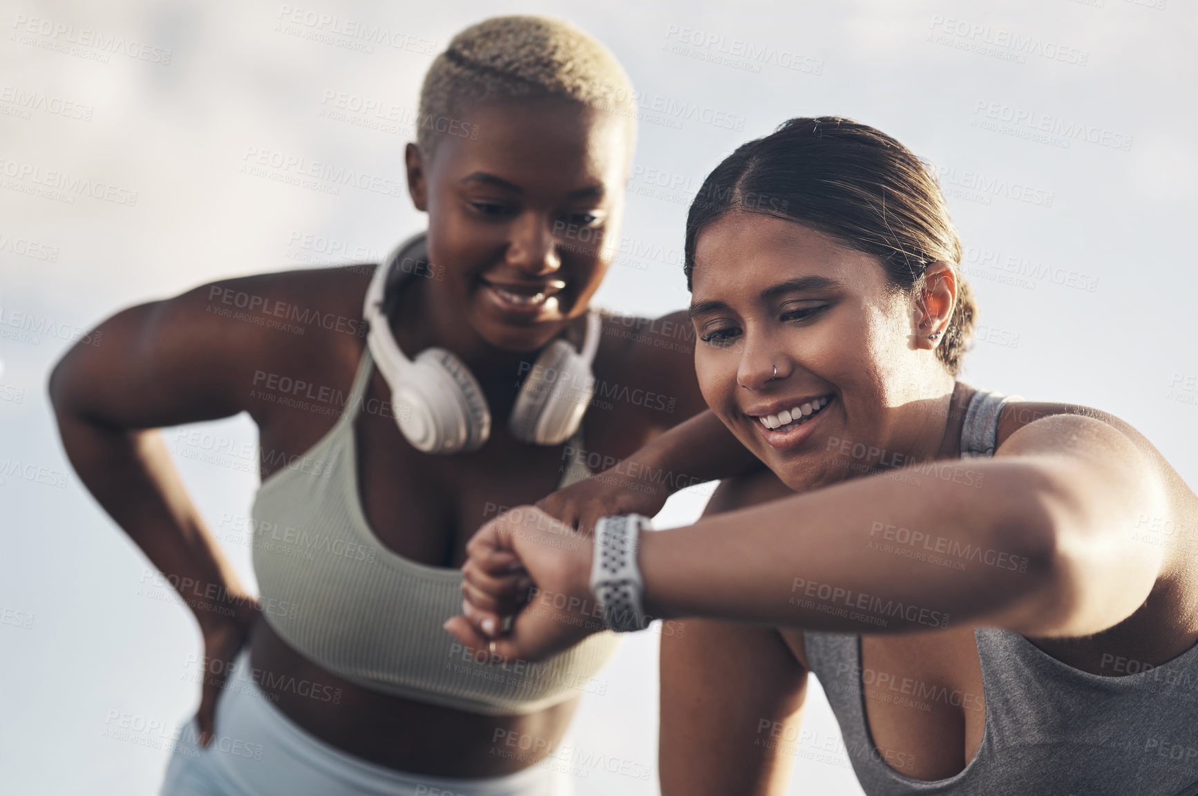 Buy stock photo Shot of two young women checking the time while out for a workout together