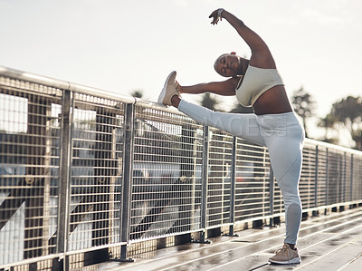 Buy stock photo Shot of a young woman stretching on a footbridge