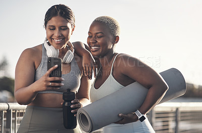 Buy stock photo Shot of two friends looking at something on a cellphone while out for a workout