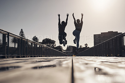 Buy stock photo Silhouette shot of two women jumping for joy while out for a workout