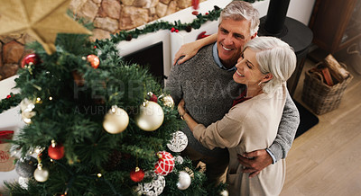 Buy stock photo Shot of a happy senior couple decorating their Christmas tree at home
