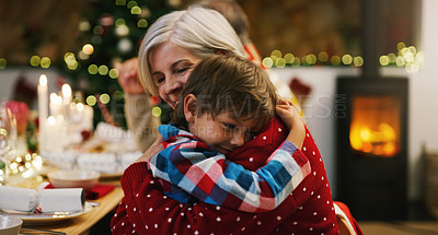 Buy stock photo Shot of an affectionate senior woman hugging her grandson during a Christmas dinner party at home