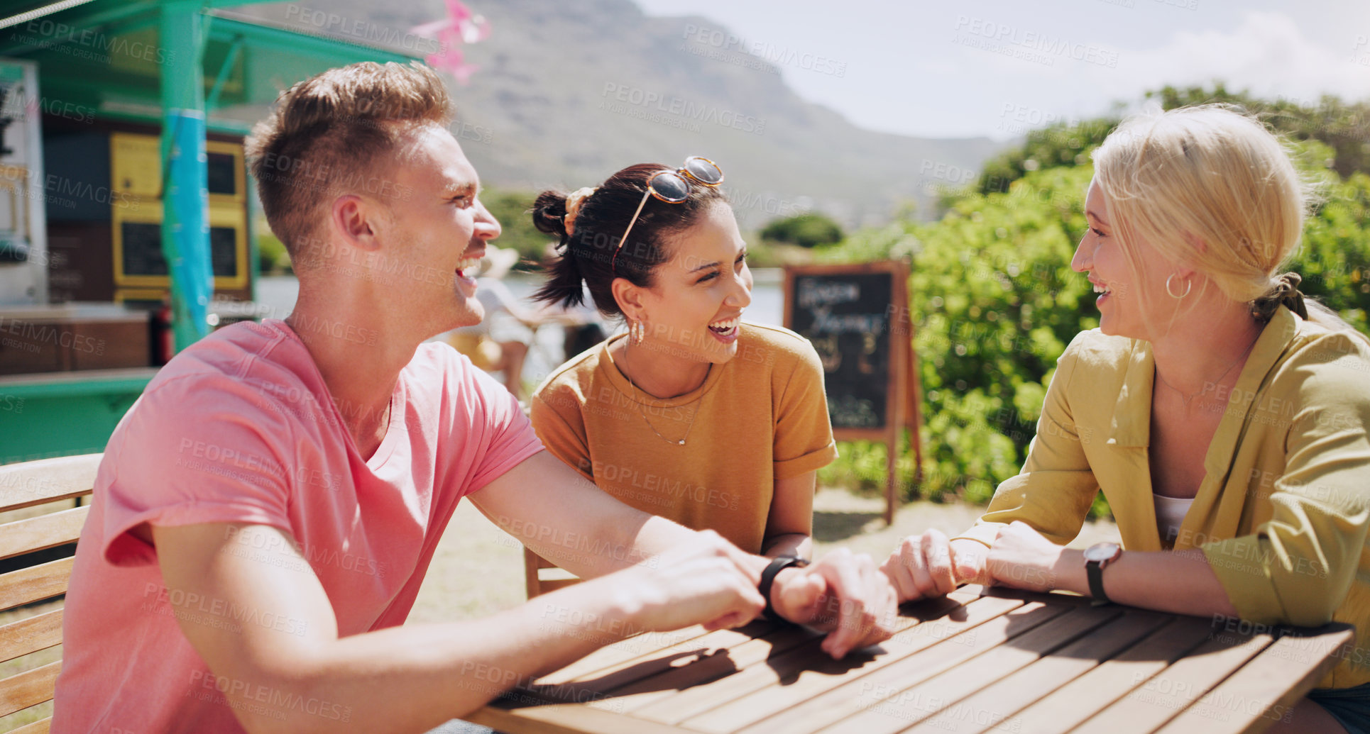 Buy stock photo Funny, friends and talking at outdoor table of restaurant, communication and happy people bonding together. Group, smile and laughing at conversation in nature for comedy, joke or story in summer