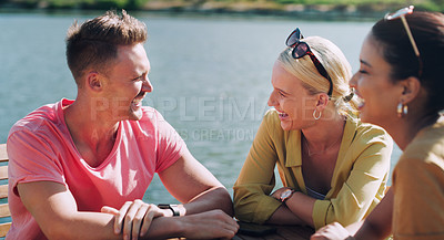 Buy stock photo Funny, friends and talking outdoor by ocean for vacation, gossip and happy people bonding together. Group, smile and laughing at conversation at sea in nature for holiday, travel or story in summer