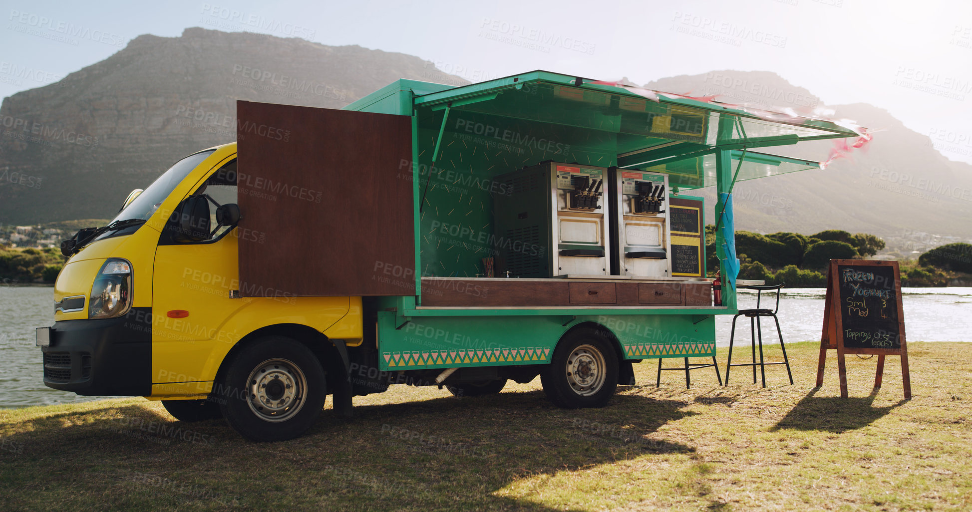 Buy stock photo Food truck next to a lake out in nature open for business on a sunny day during summer. Food van selling frozen yogurt and water as refreshments and a quick snack for hikers, tourists and locals