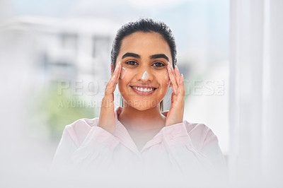 Buy stock photo Cropped shot of a beautiful young woman applying moisturiser to her face