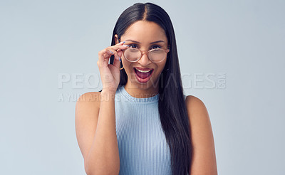Buy stock photo Cropped portrait of an attractive young woman peering over her glasses while standing against a grey background in studio