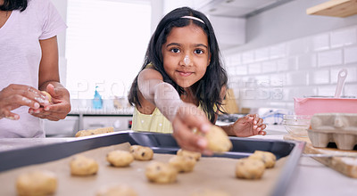 Buy stock photo Shot of an adorable little girl placing cookie dough on a baking tray