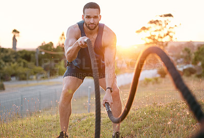 Buy stock photo Shot of a sporty young man doing heavy rope training outside
