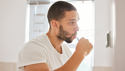 Buy stock photo Shot of a young man brushing his teeth in the morning