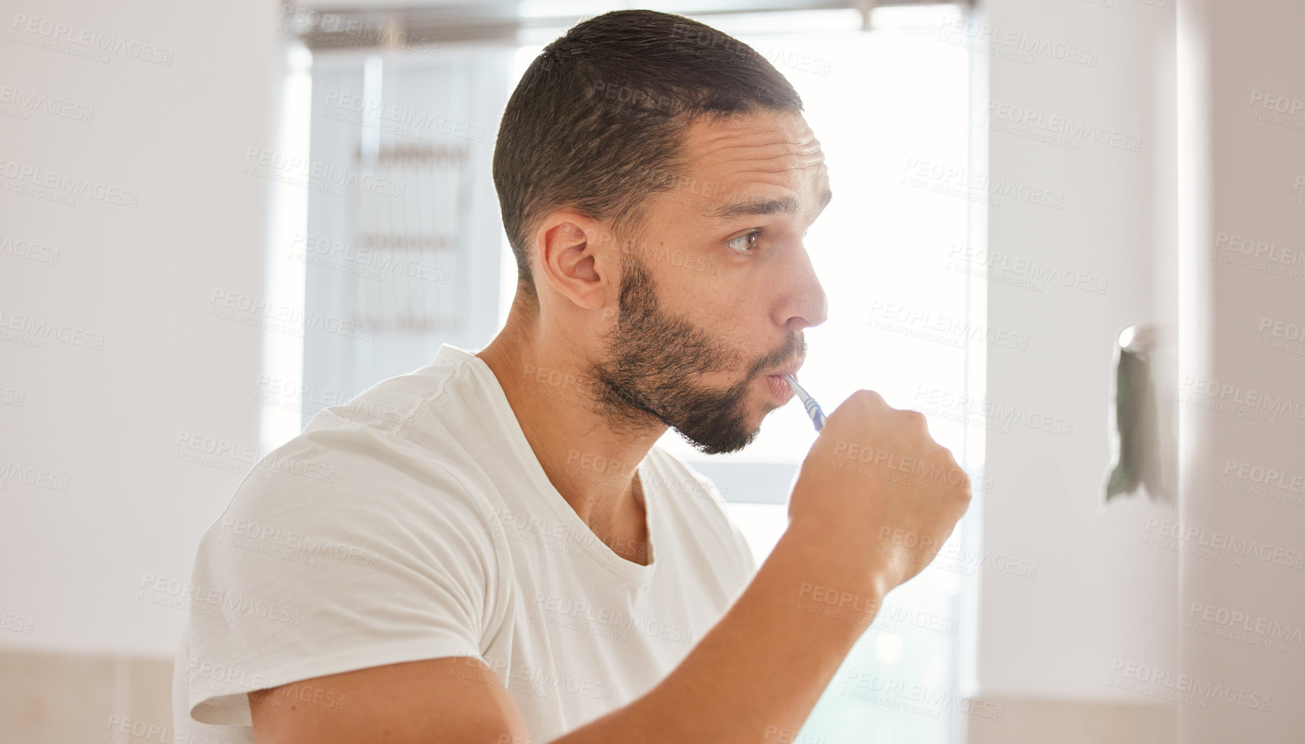 Buy stock photo Shot of a young man brushing his teeth in the morning