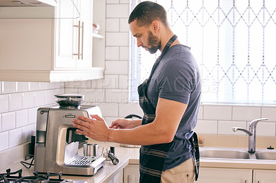 Buy stock photo Shot of a young man using a coffee machine to make himself a beverage