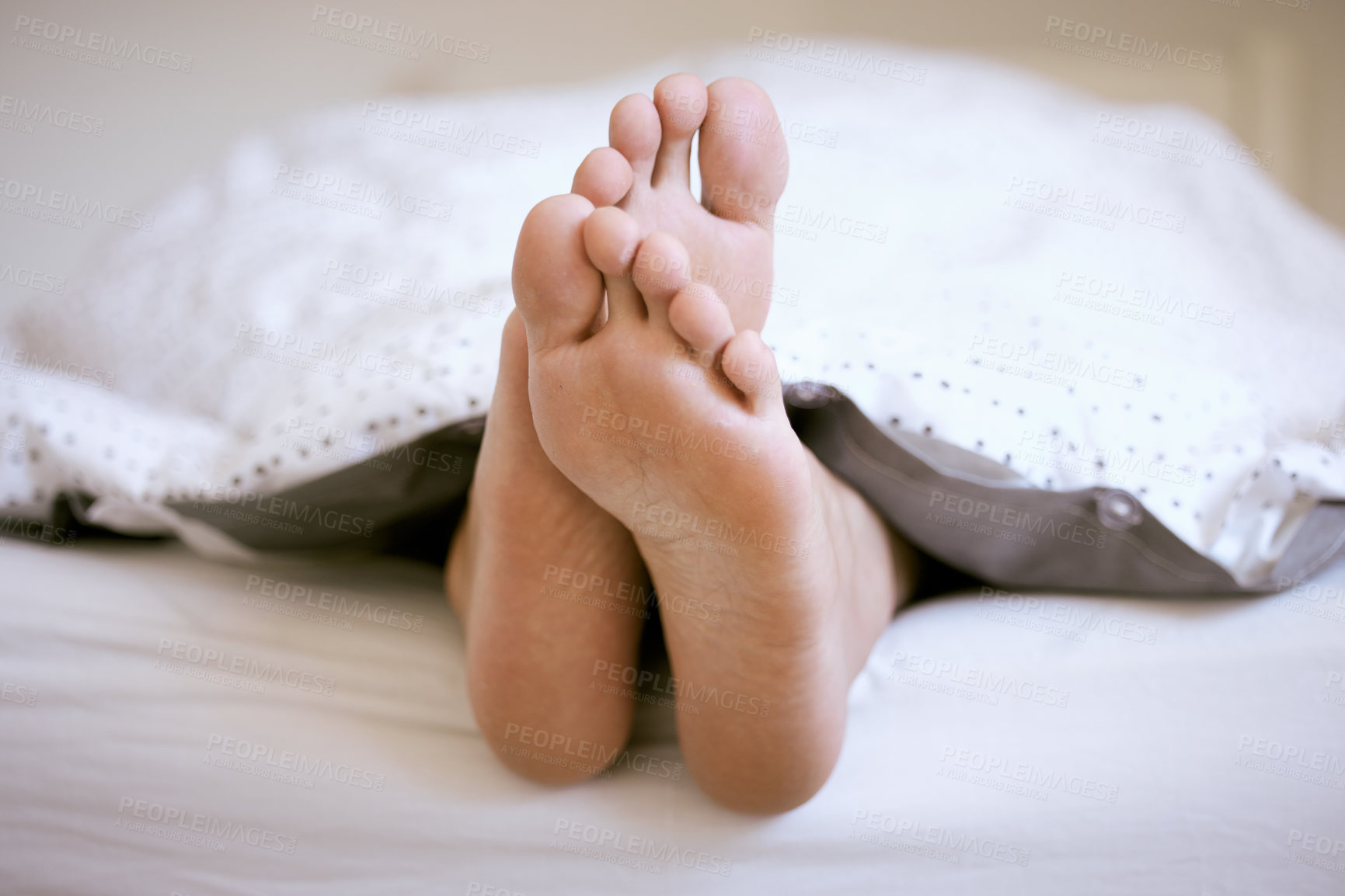 Buy stock photo Shot of an unrecognizable mans feet poking out of the bed sheets