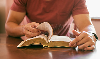 Buy stock photo Shot of a young man sitting at a table reading his bible