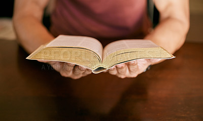 Buy stock photo Shot of a young man sitting down holding a bible in his hands