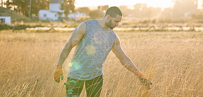 Buy stock photo Shot of a young man walking through a field of wheat while touching it