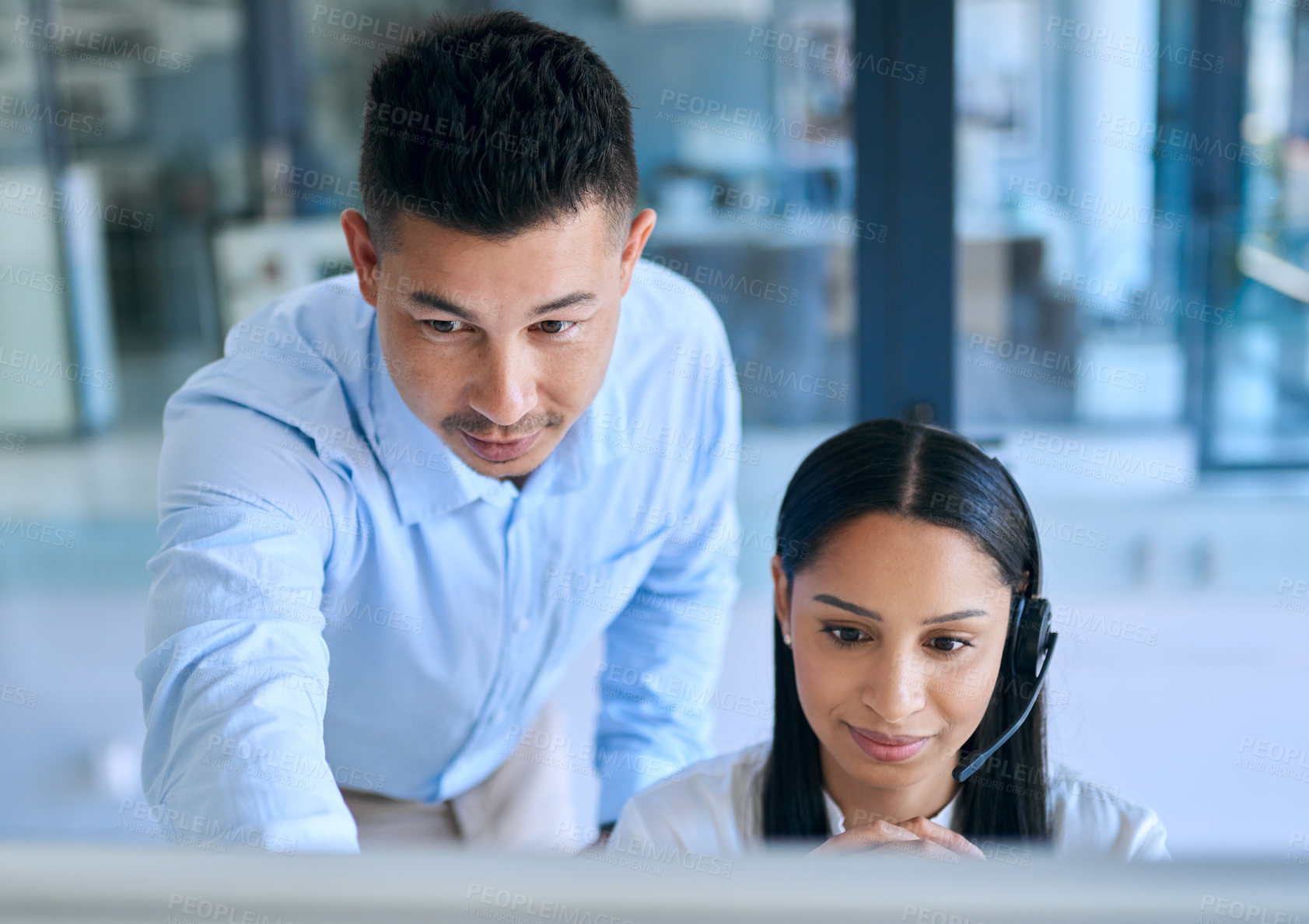 Buy stock photo Shot of a young man helping his colleague in a modern call centre