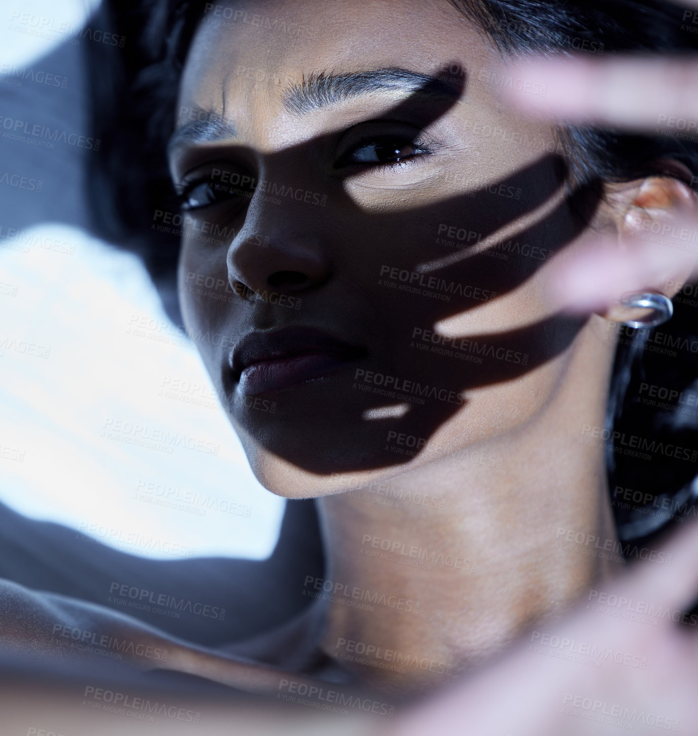 Buy stock photo Shot of a young woman shielding her face from a bright light