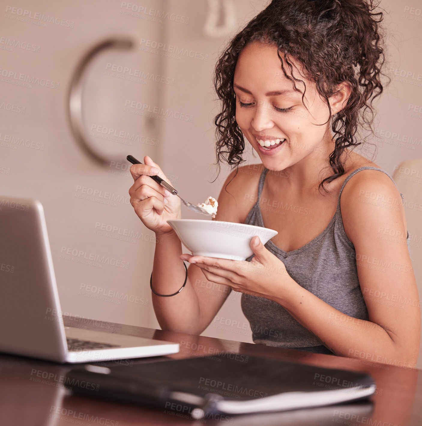 Buy stock photo Shot of a woman eating breakfast while sitting at her laptop