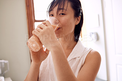 Buy stock photo Shot of a young woman enjoying a smoothie in her kitchen at home