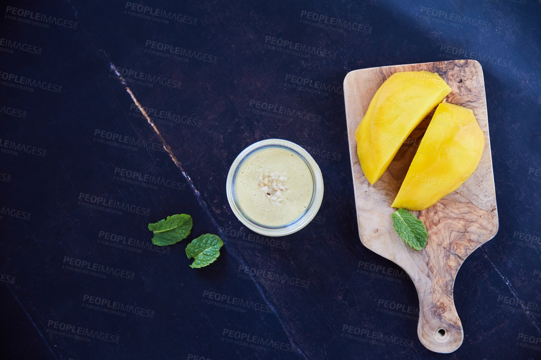 Buy stock photo Overhead shot of a mango and mint smoothie on a black background