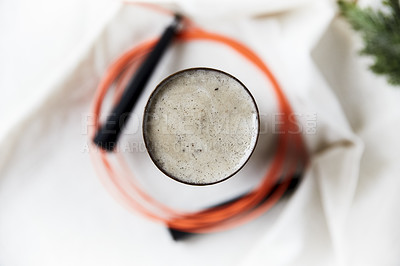 Buy stock photo Overhead shot of a chia seed smoothie surrounded by a jumping rope on a white table cloth