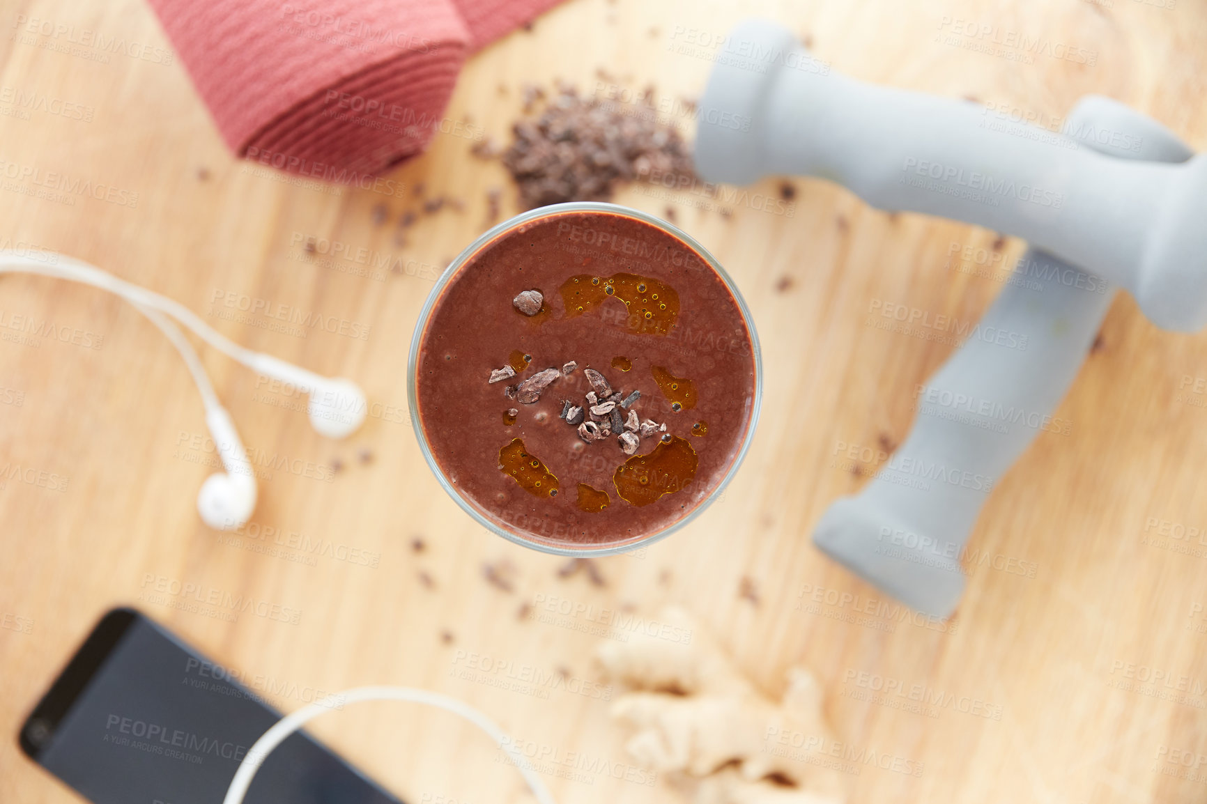 Buy stock photo Overhead shot of a cocoa smoothie surrounded by fitness equipment on a wooden table