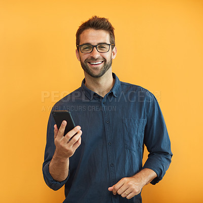 Buy stock photo Cropped portrait of a handsome young businessman standing against a yellow studio background and using his cellphone