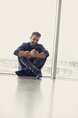 Buy stock photo Full length shot of a handsome young businessman sitting alone in an airport terminal and using his cellphone