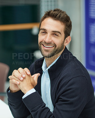Buy stock photo Cropped portrait of a handsome young businessman sitting alone in an office space during the day