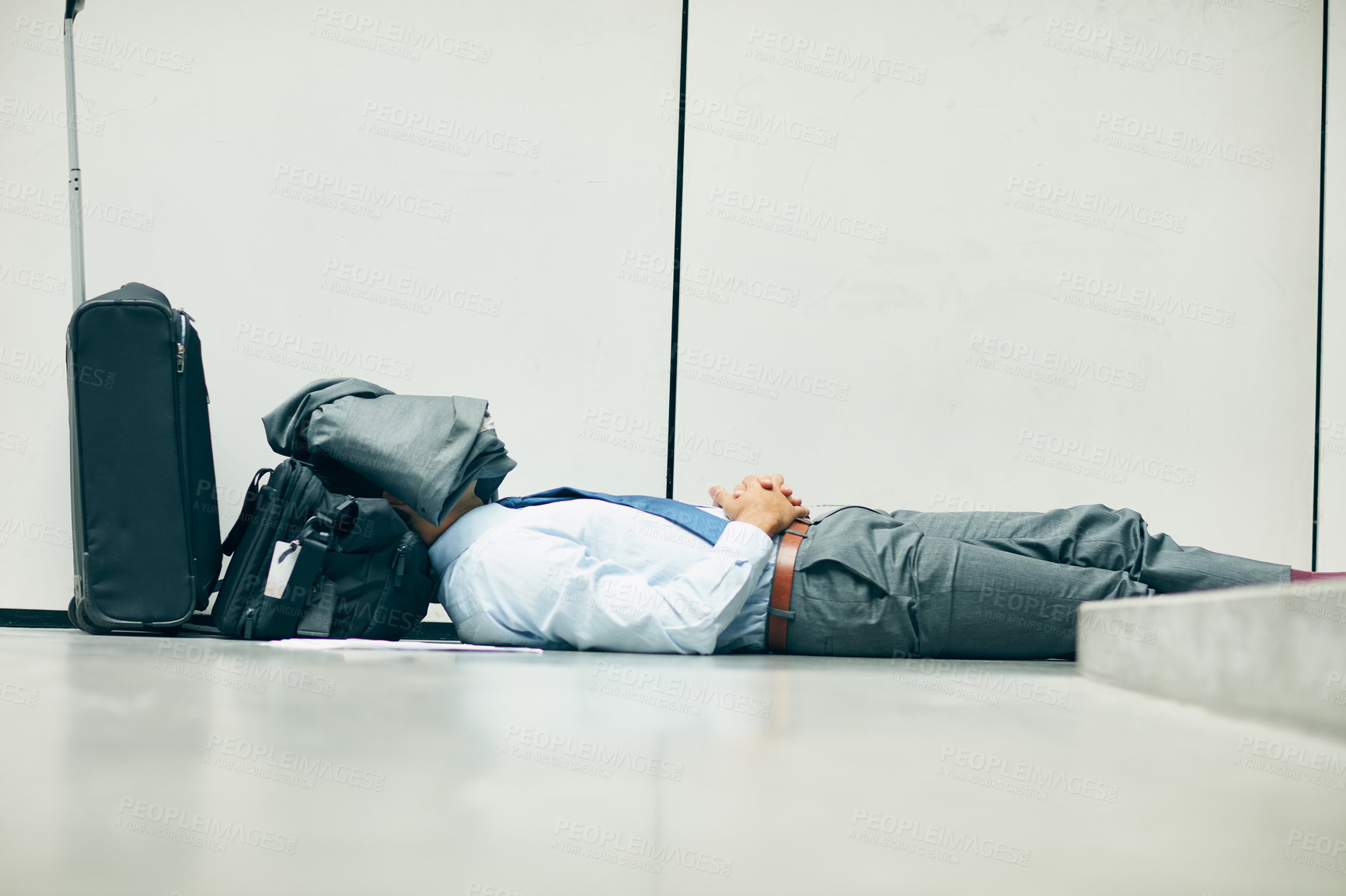 Buy stock photo Cropped shot of an unrecognizable businessman sleeping in an airport terminal and covering his face with his jacket