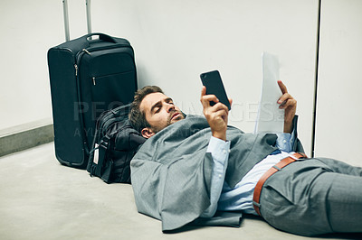 Buy stock photo Cropped shot of a handsome young businessman lying down in an airport terminal and looking confused while using his cellphone